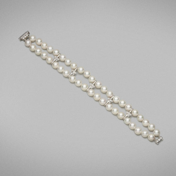 A BUNDA 'Apus' double-strand bracelet, featuring Akoya pearls, strung knotted with a high polished 18ct white gold diamond set rectangular clasp, and high polished 18ct white gold diamond set spacers.  The 44 pearls are round in shape, white in colour, have excellent lustre and clean skins and range in size from 7.00 - 7.45mm  Characteristics of Additional Diamonds: 36 = 0.50ct, F Colour / VS Clarity  Clasp is stamped 'BUNDA'  Total Weight: 31.76 grams