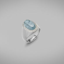  A BUNDA "Corvus" ring mounted in all 18 carat white gold and bezel set with a single oval cabochon pale blue Tourmaline, surrounded with a line of thread set diamonds. 18ct white gold setting has elegant brushed gold finish.  The Tourmaline weighs 6.50 carats.  Characteristics of diamonds: 31 = 0.15ct, F colour, VS clarity.  Weight of Ring: 9.40 grams.   
