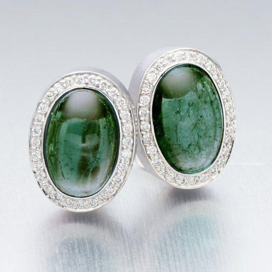 A pair of BUNDA 'Corvus' tourmaline earrings in 18ct white gold, featuring a pair of cabochon cut green tourmalines, bezel set and surrounded with threadset round brilliant cut diamonds, fitted with a post and keyhole clip fitting.  Weight of tourmalines: 2 = 14.50ct.  Characteristics of diamonds: 68 = 0.34ct, F colour, VS clarity.