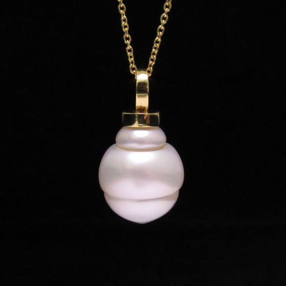 A BUNDA Cultured South Sea pearl 'Eva' pendant in 18 carat yellow gold, featuring a circle drop shaped pearl with a clean skin and an excellent lustre, white in colour with pink overtones, fitted with an 18 carat yellow gold Trace chain.  Dimensions of pearl: = 15.00 - 18.40mm  Total weight: 9.42g