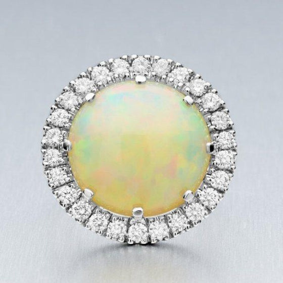 A BUNDA 'Valentin', hand crafted, Opal and diamond ring in platinum, featuring a beautiful Ethiopian Opal, surrounded with claw set round brilliant cut diamonds.  Characteristics of Opal: 1 = 11.55ct, featuring colours of white with green, blue and orange. Origin: Ethiopia  Characteristics of diamonds: 26 = 1.09ct, F colour, VS clarity.  Total weight of Ring: 16.43 grams